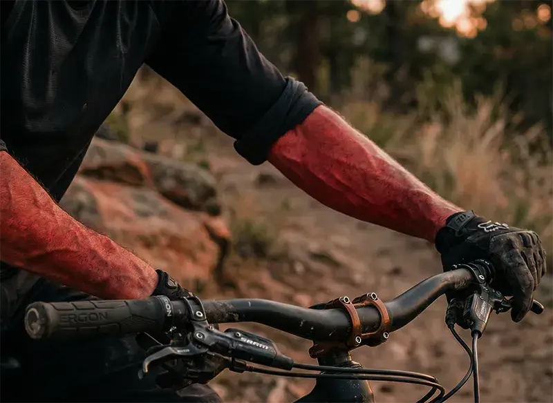 Arms of a mountain biker suffering arm pump while gripping a mountain bike handlebar